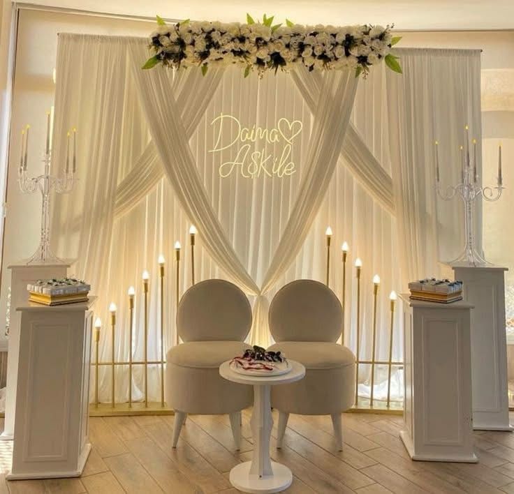 Salon d'honneur : deux fauteuils devant des drapés ivoire, candélabres et néon